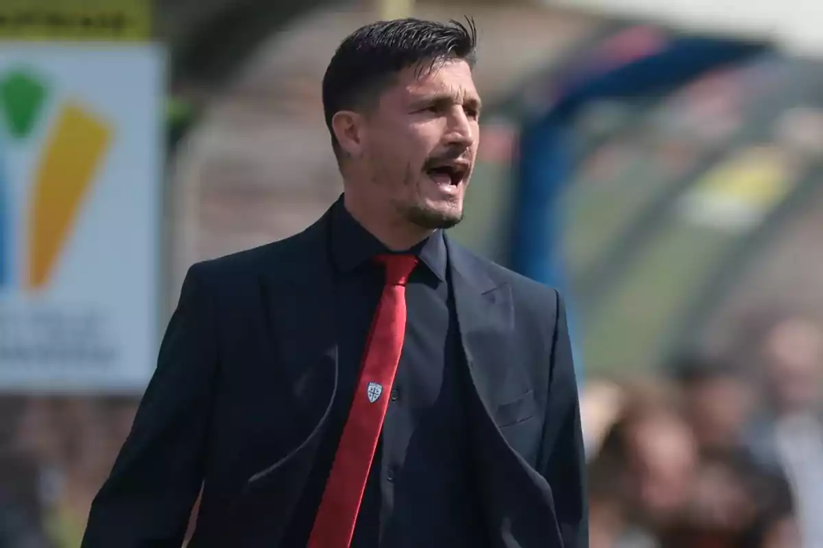 Man in a dark suit and red tie shouting in an outdoor sports setting Man in a dark suit and red tie shouting in an outdoor sports setting