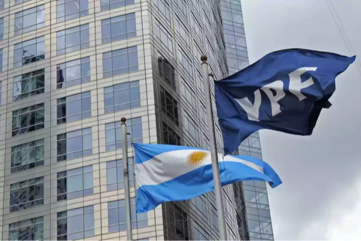 Banderas de YPF y de Argentina ondeando frente a un edificio de oficinas moderno
