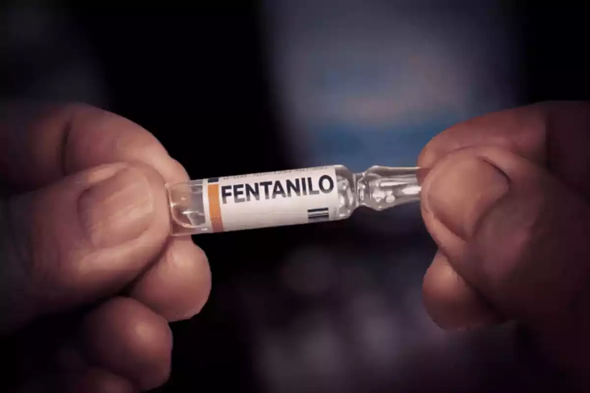Manos sosteniendo una ampolleta de vidrio etiquetada con la palabra fentanilo