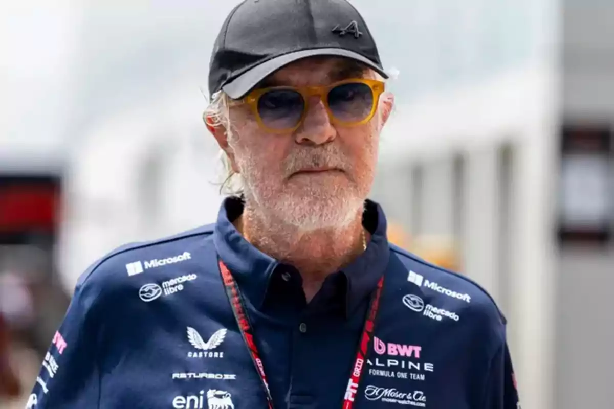 Hombre mayor con barba y gafas de sol usando gorra negra y camisa azul del equipo Alpine de Fórmula 1 Hombre mayor con barba y gafas de sol usando gorra negra y camisa azul del equipo Alpine de Fórmula 1