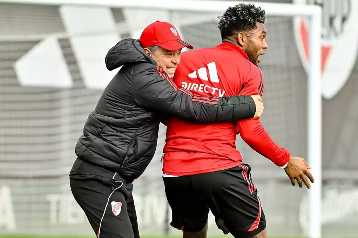 River Plate’s coach and player smile and hug during a training session on the field. River Plate’s coach and player smile and hug during a training session on the field.
