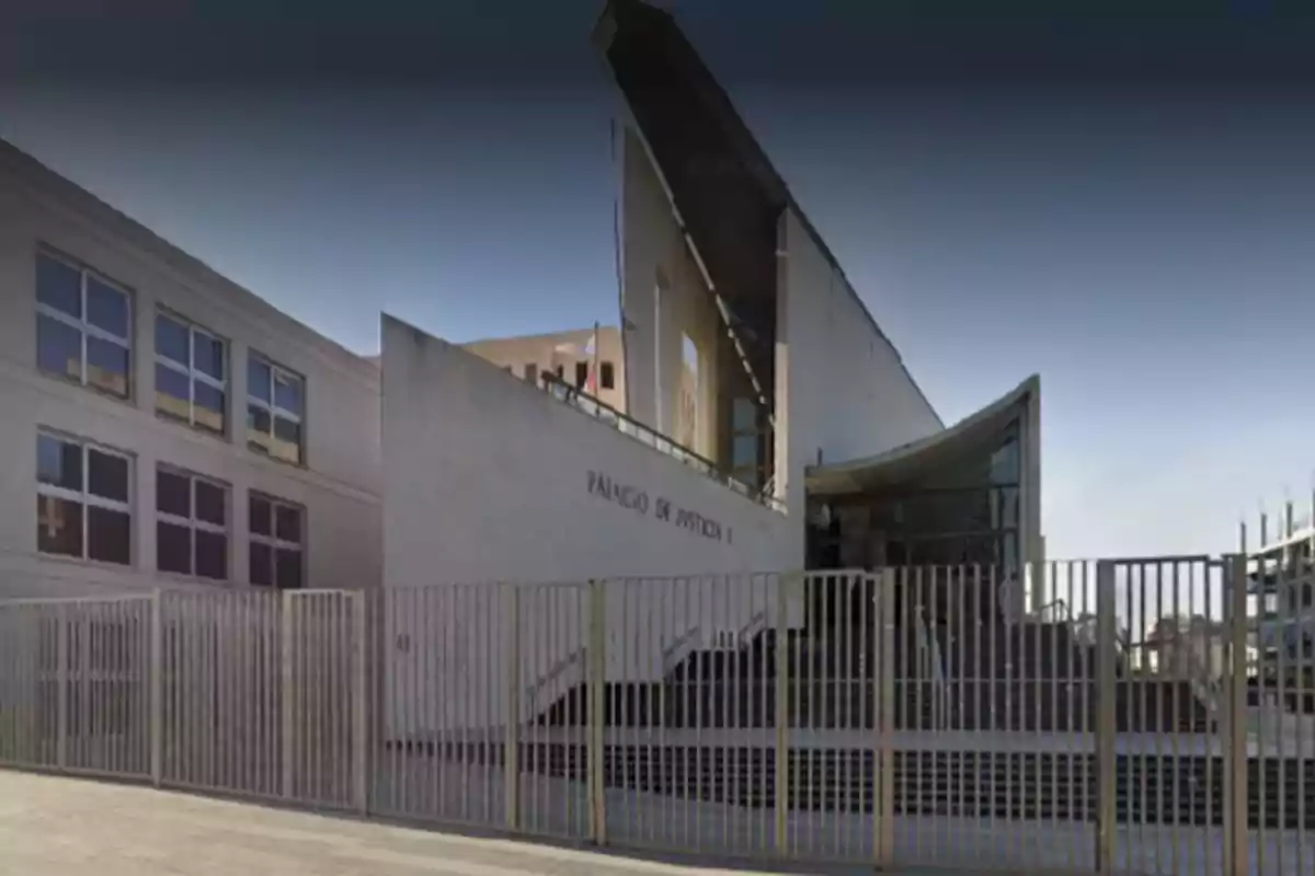 Modern concrete building with large windows and a metal gate in front that has a sign reading Palace of Justice Modern concrete building with large windows and a metal gate in front that has a sign reading Palace of Justice