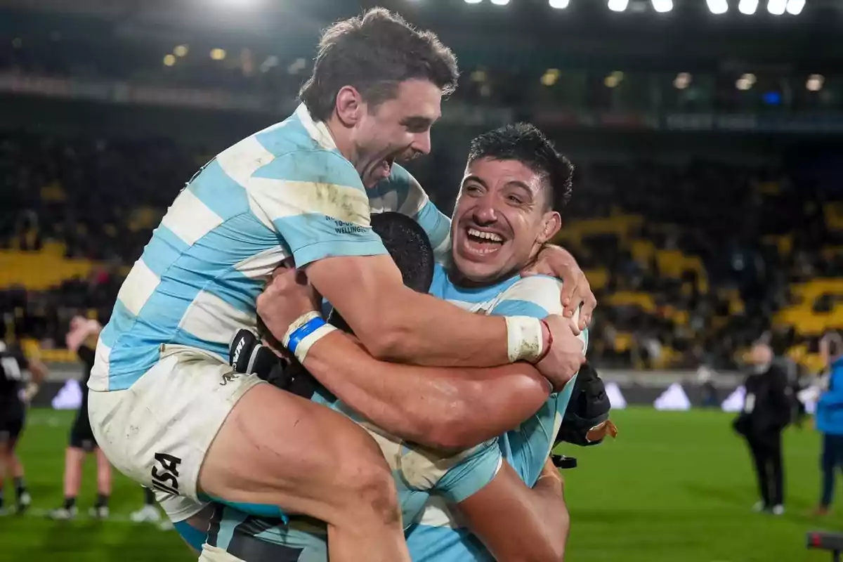 Argentinian rugby players celebrate hugging and smiling on the field after a match. Argentinian rugby players celebrate hugging and smiling on the field after a match.