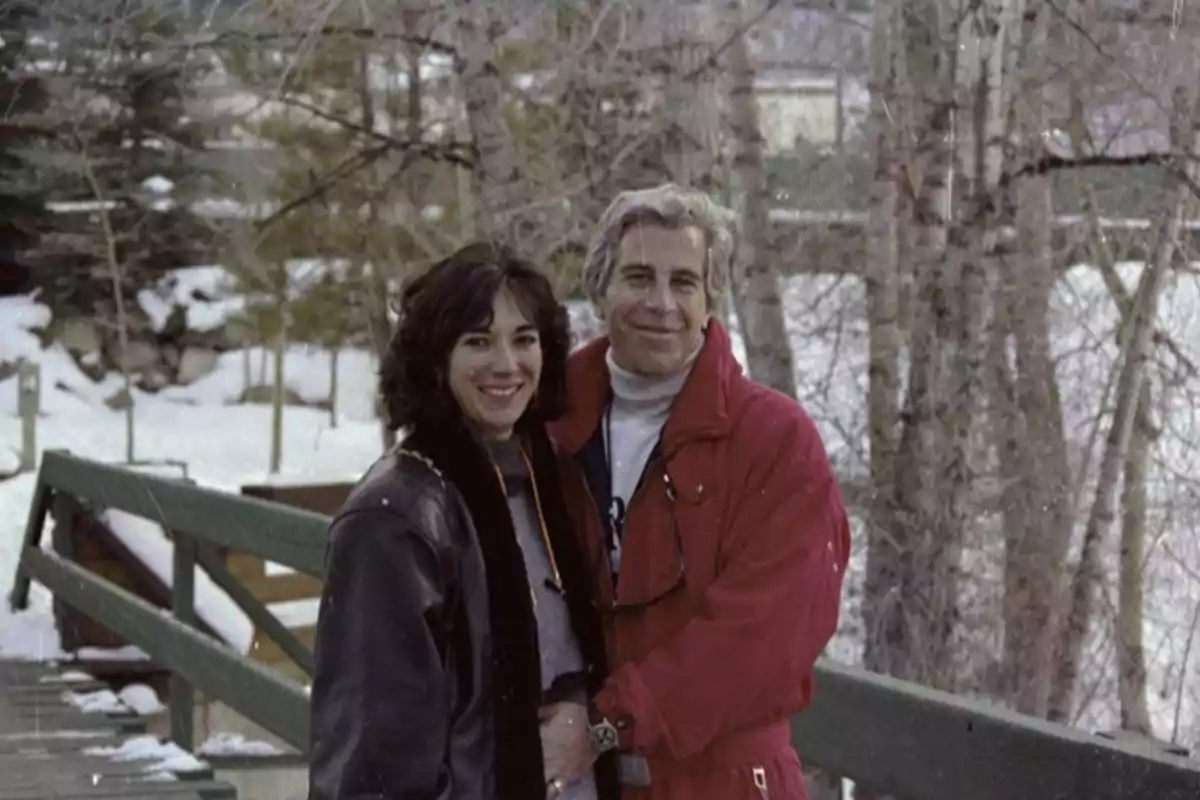 Couple hugging on a wooden bridge in a snowy setting with trees in the background
