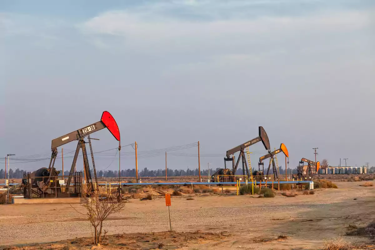 Several oil wells operating in an arid field under a clear sky Several oil wells operating in an arid field under a clear sky