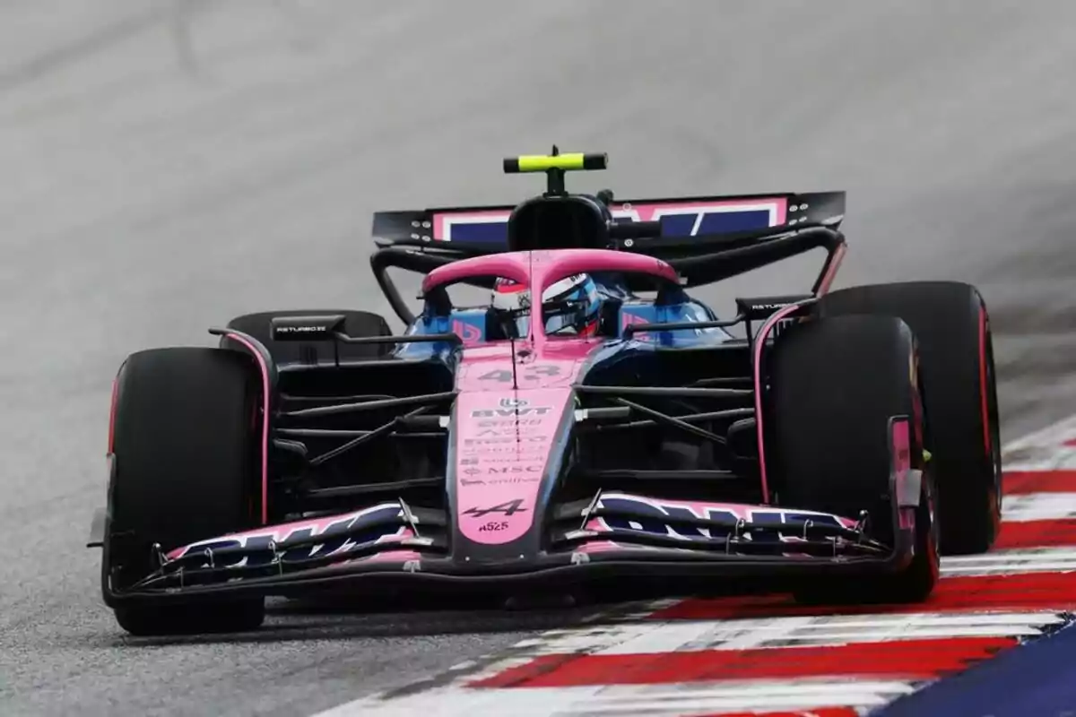 Pink and blue Formula 1 car driving on a racetrack Pink and blue Formula 1 car driving on a racetrack