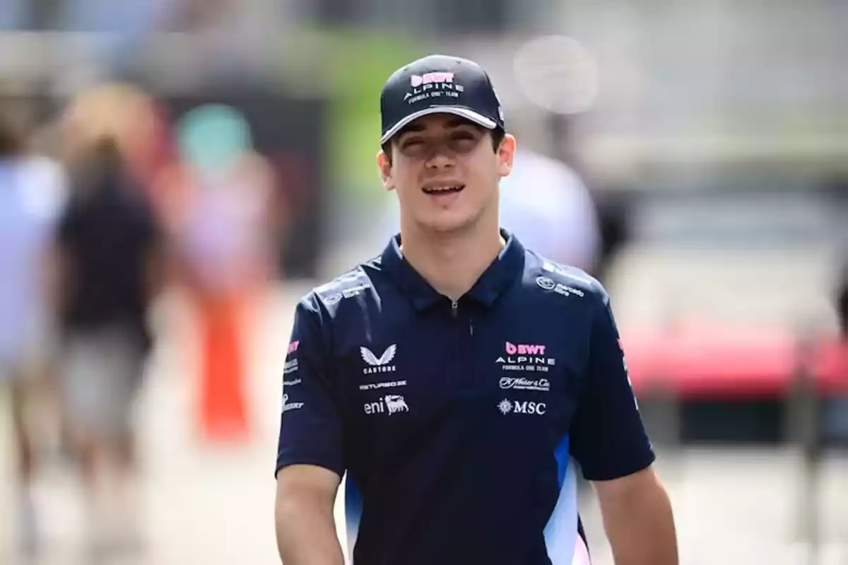 Joven con gorra y camiseta de un equipo de automovilismo caminando al aire libre en un ambiente deportivo Joven con gorra y camiseta de un equipo de automovilismo caminando al aire libre en un ambiente deportivo