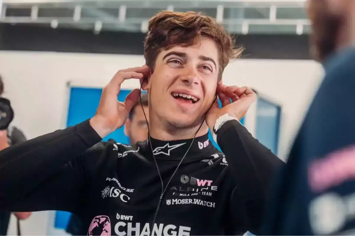 Young race car driver smiling while putting on headphones in a workshop or race garage setting