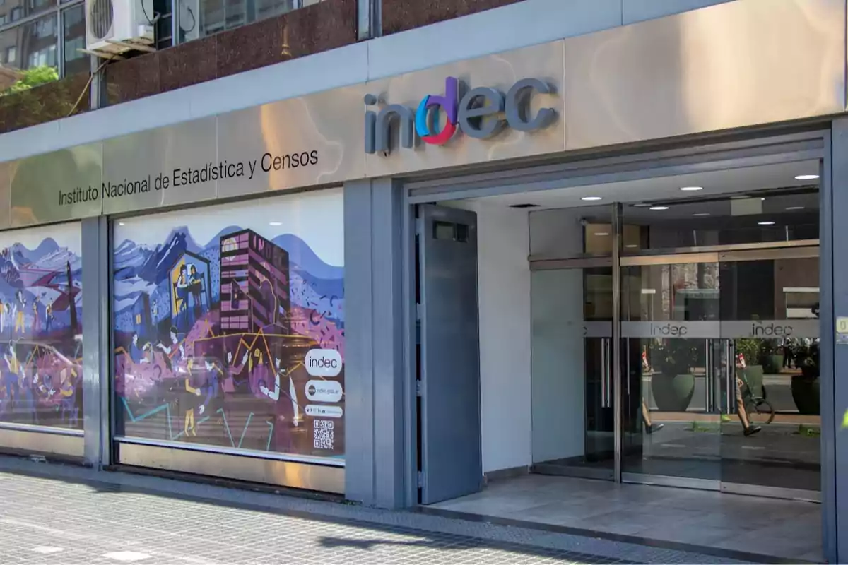 Facade of the building of the National Institute of Statistics and Censuses of Argentina with glass doors and a colorful mural on the window.
