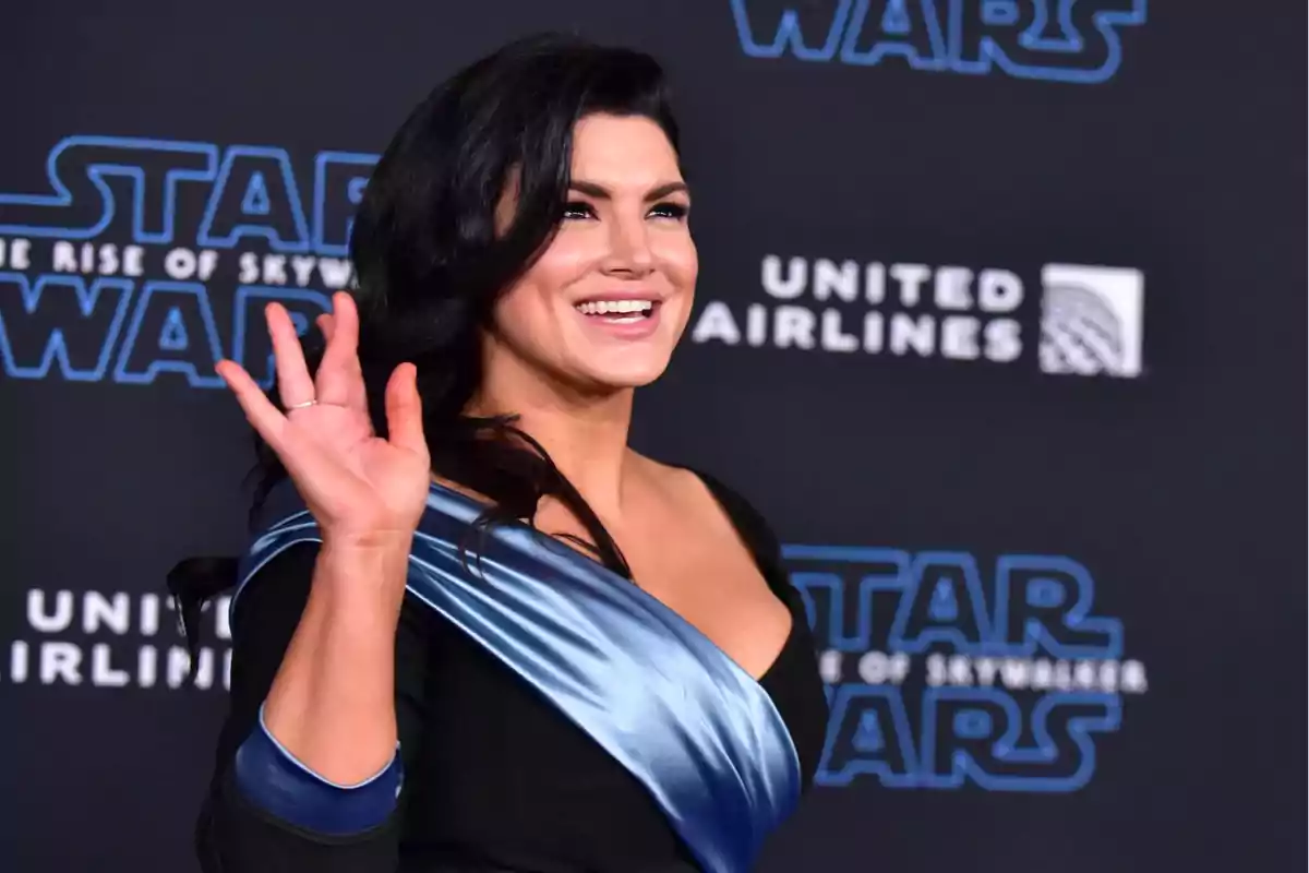 Mujer sonriendo y saludando en una alfombra roja con fondo de Star Wars