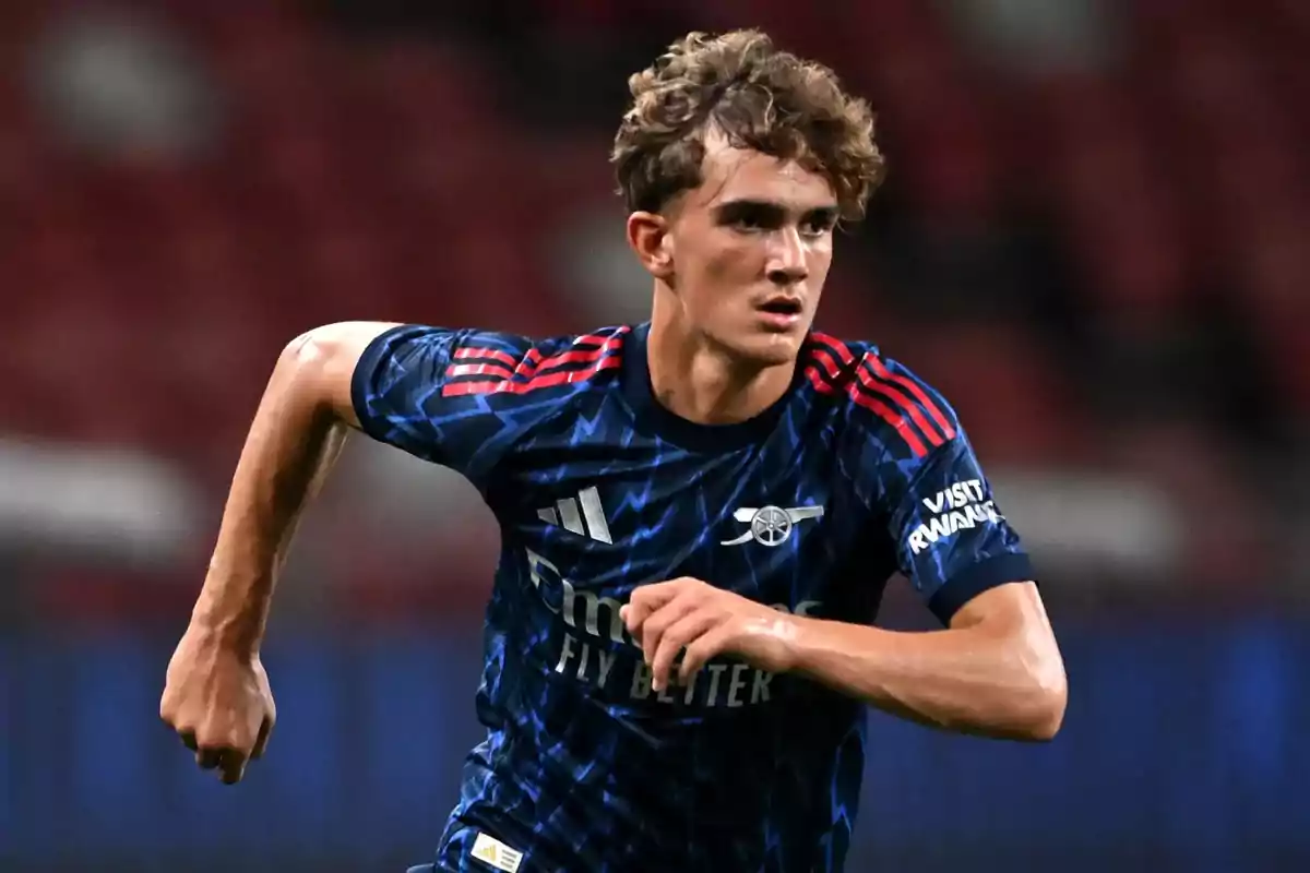 Young player in a blue Arsenal uniform running on the field during a match