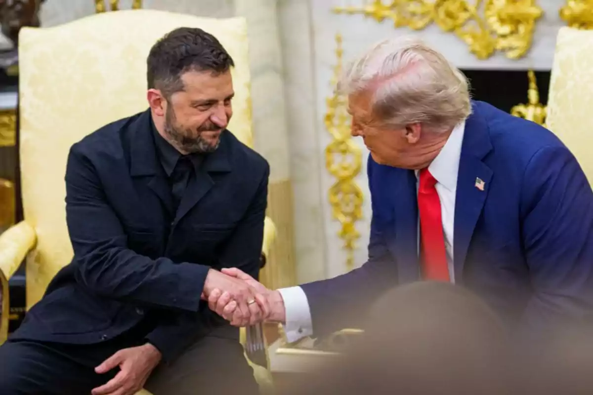 Two seated men shake hands and smile at each other in an elegant room with yellow armchairs and golden details.