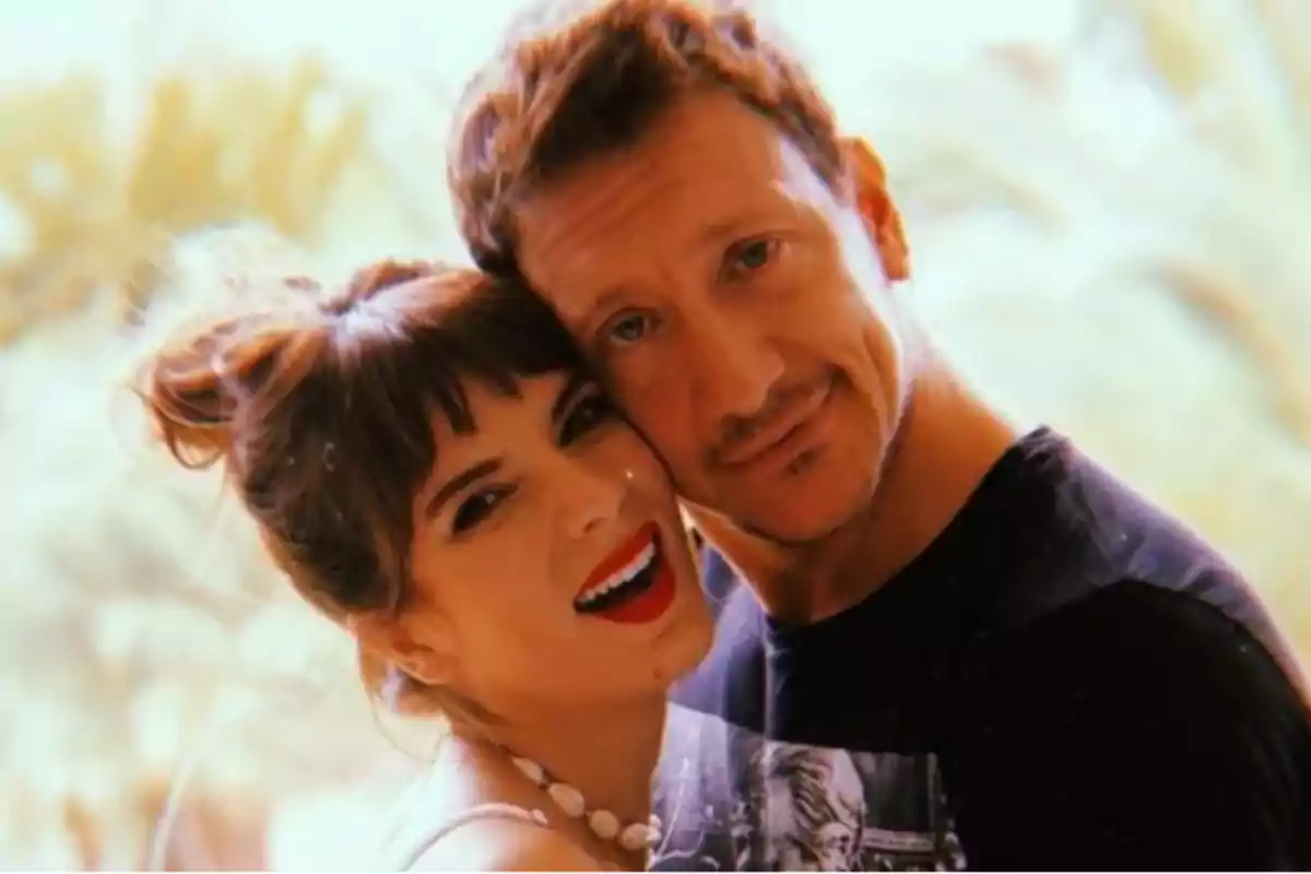 Couple hugging and smiling in front of a blurred light-toned background
