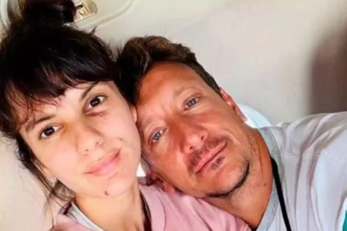 Una pareja se toma una selfie juntos mientras están recostados y sonríen suavemente a la cámara
