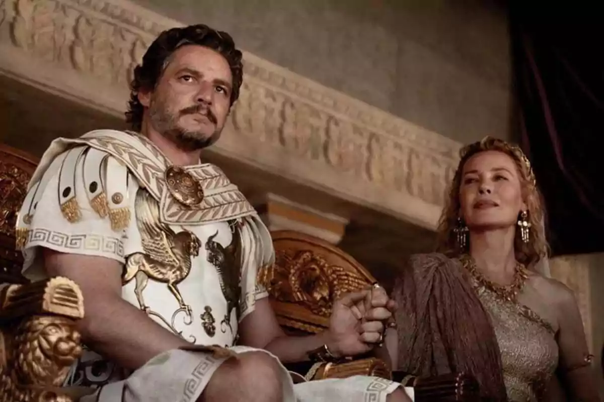 Two people dressed in ancient Roman costumes are sitting on a golden throne inside a building decorated with classical reliefs. Two people dressed in ancient Roman costumes are sitting on a golden throne inside a building decorated with classical reliefs.