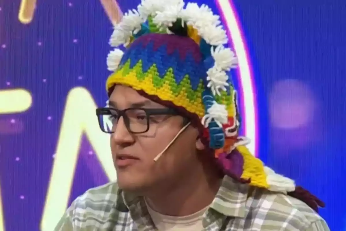 Hombre con gafas y gorro andino colorido hablando en un programa de televisión