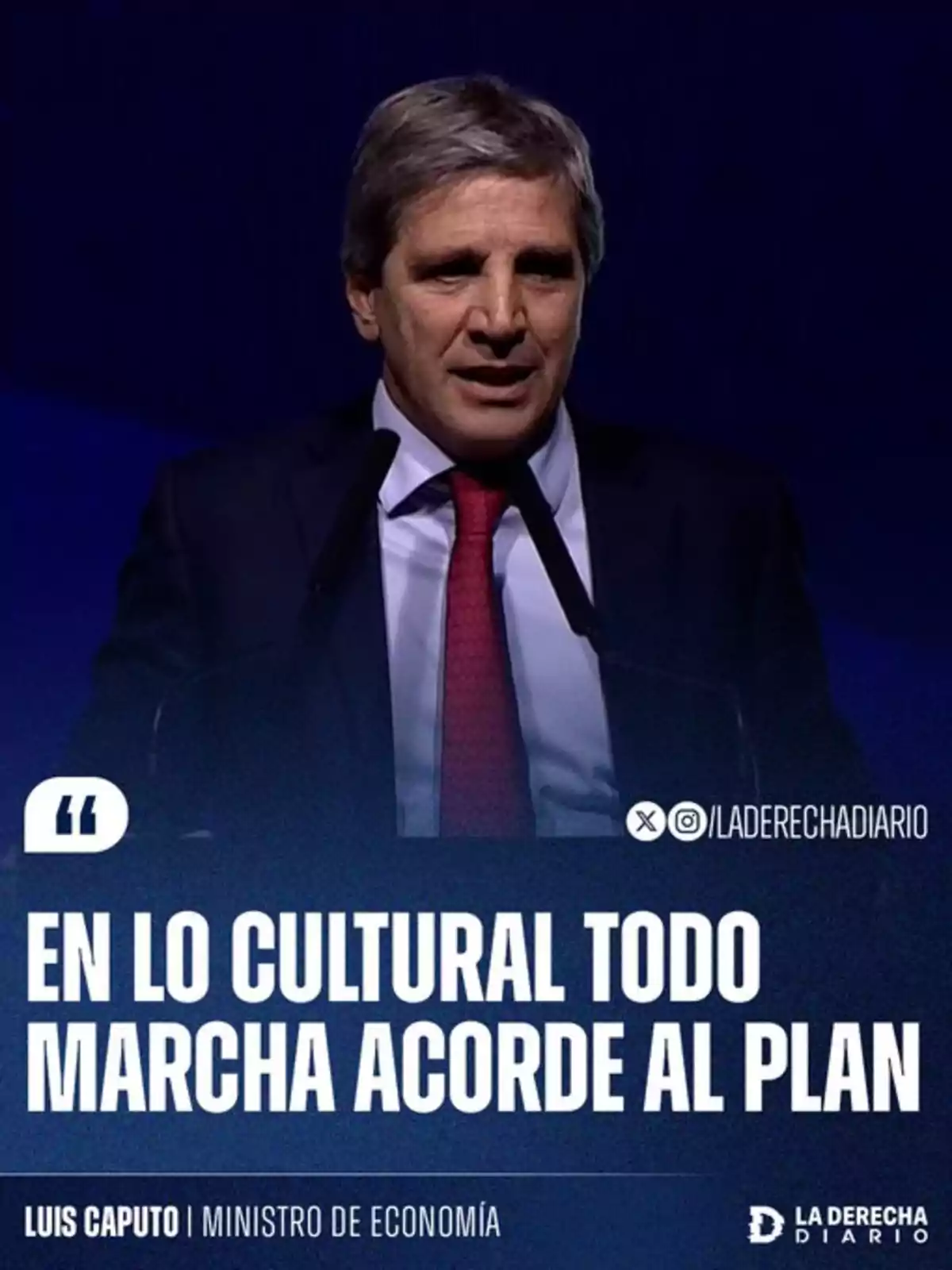 Hombre de cabello canoso con traje oscuro y corbata roja hablando frente a un micrófono con fondo azul y texto que dice en lo cultural todo marcha acorde al plan Hombre de cabello canoso con traje oscuro y corbata roja hablando frente a un micrófono con fondo azul y texto que dice en lo cultural todo marcha acorde al plan
