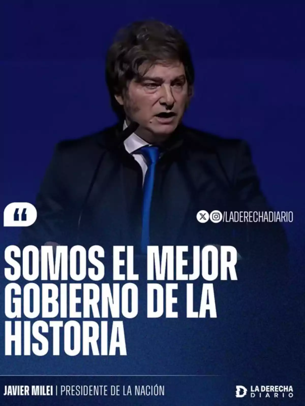 A brown-haired man in a dark suit with a blue tie speaks in front of a blue background with large text that says we are the best government in history. A brown-haired man in a dark suit with a blue tie speaks in front of a blue background with large text that says we are the best government in history.