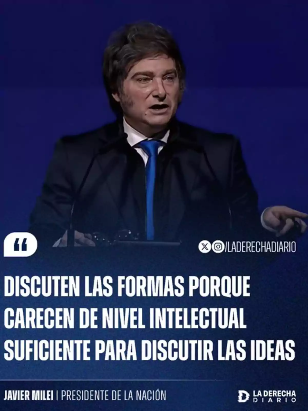 Brown-haired man in a dark suit speaking in front of a microphone with a blue background and a phrase in white letters about the discussion of ideas and intellectual level Brown-haired man in a dark suit speaking in front of a microphone with a blue background and a phrase in white letters about the discussion of ideas and intellectual level