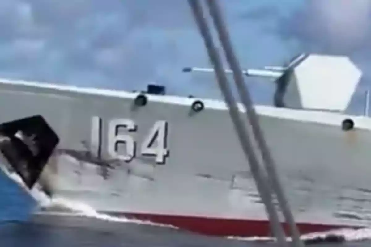 Buque gris con el número 164 navegando en el mar bajo un cielo parcialmente nublado