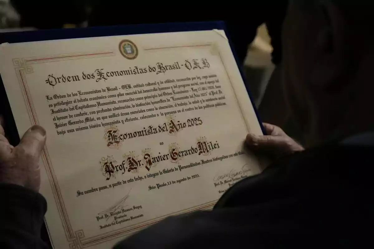 Persona sostiene un diploma que reconoce a Javier Gerardo Milei como Economista del Año 2025 otorgado por la Orden de los Economistas de Brasil
