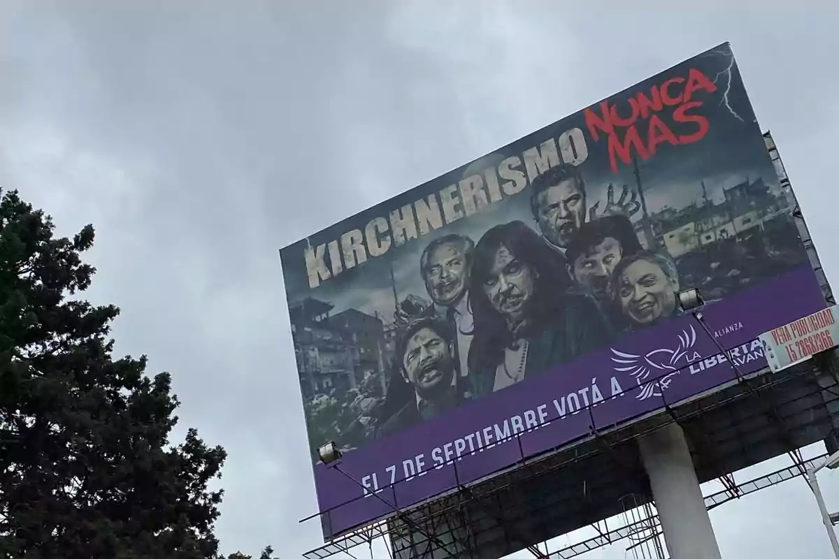 Billboard with a dark background and characters with a zombie-like appearance, featuring the text "Kirchnerism Never Again" and a purple stripe with electoral information