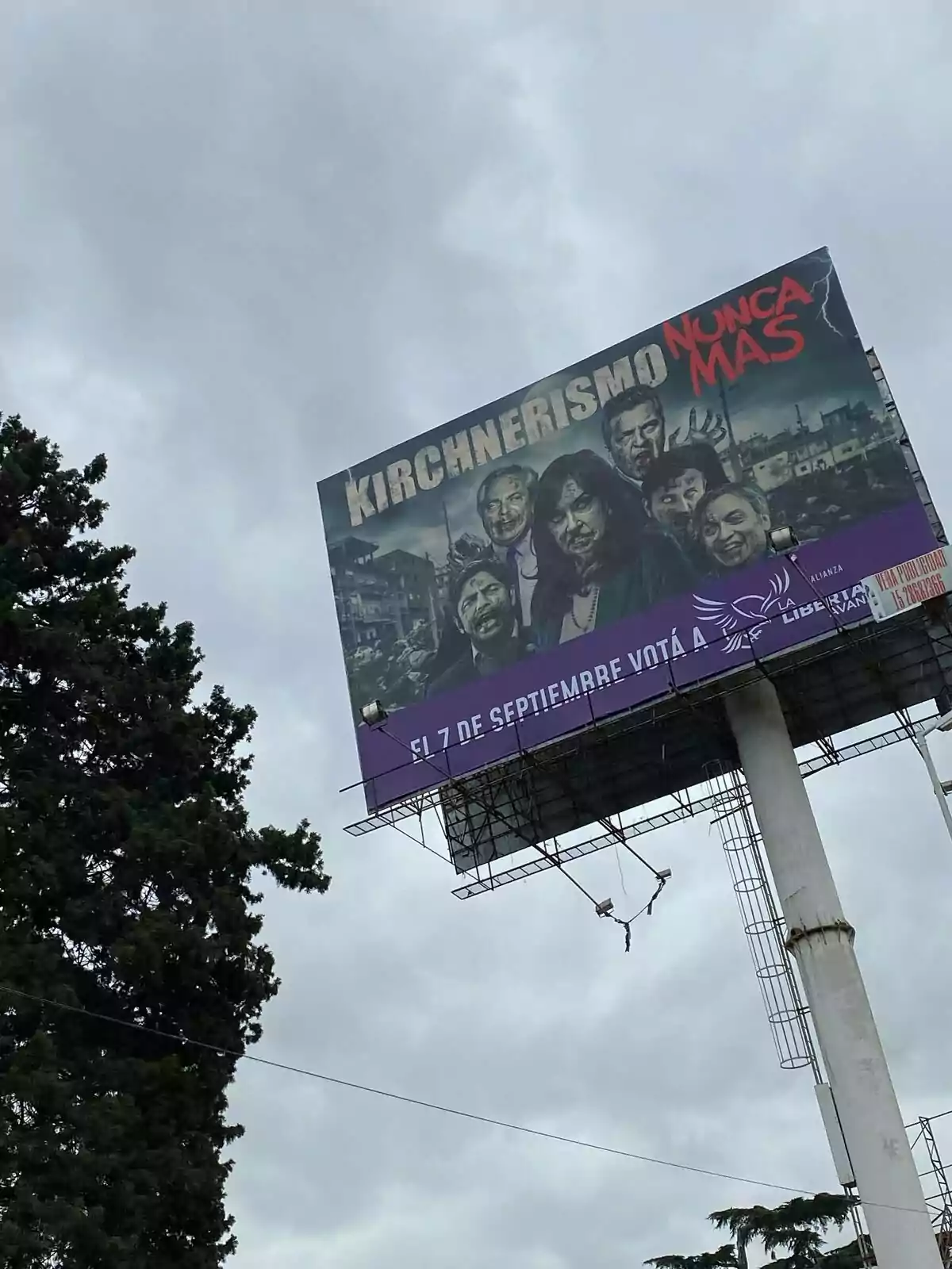 Cartel publicitario en lo alto de una estructura metálica con fondo nublado, muestra a varias personas con expresiones serias y el texto Kirchnerismo Nunca Más en letras grandes Cartel publicitario en lo alto de una estructura metálica con fondo nublado, muestra a varias personas con expresiones serias y el texto Kirchnerismo Nunca Más en letras grandes