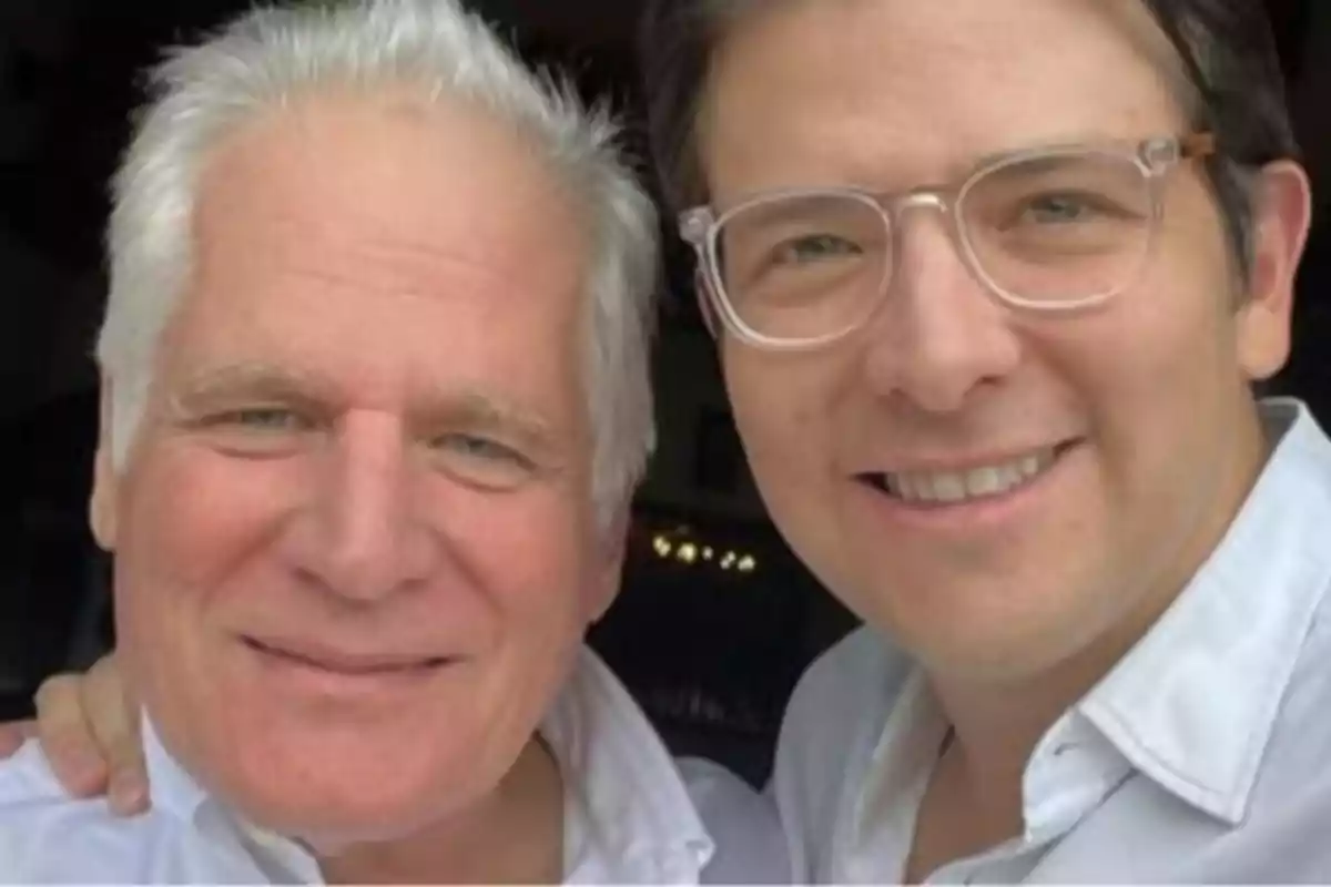 Two men smile together as they pose for a selfie.