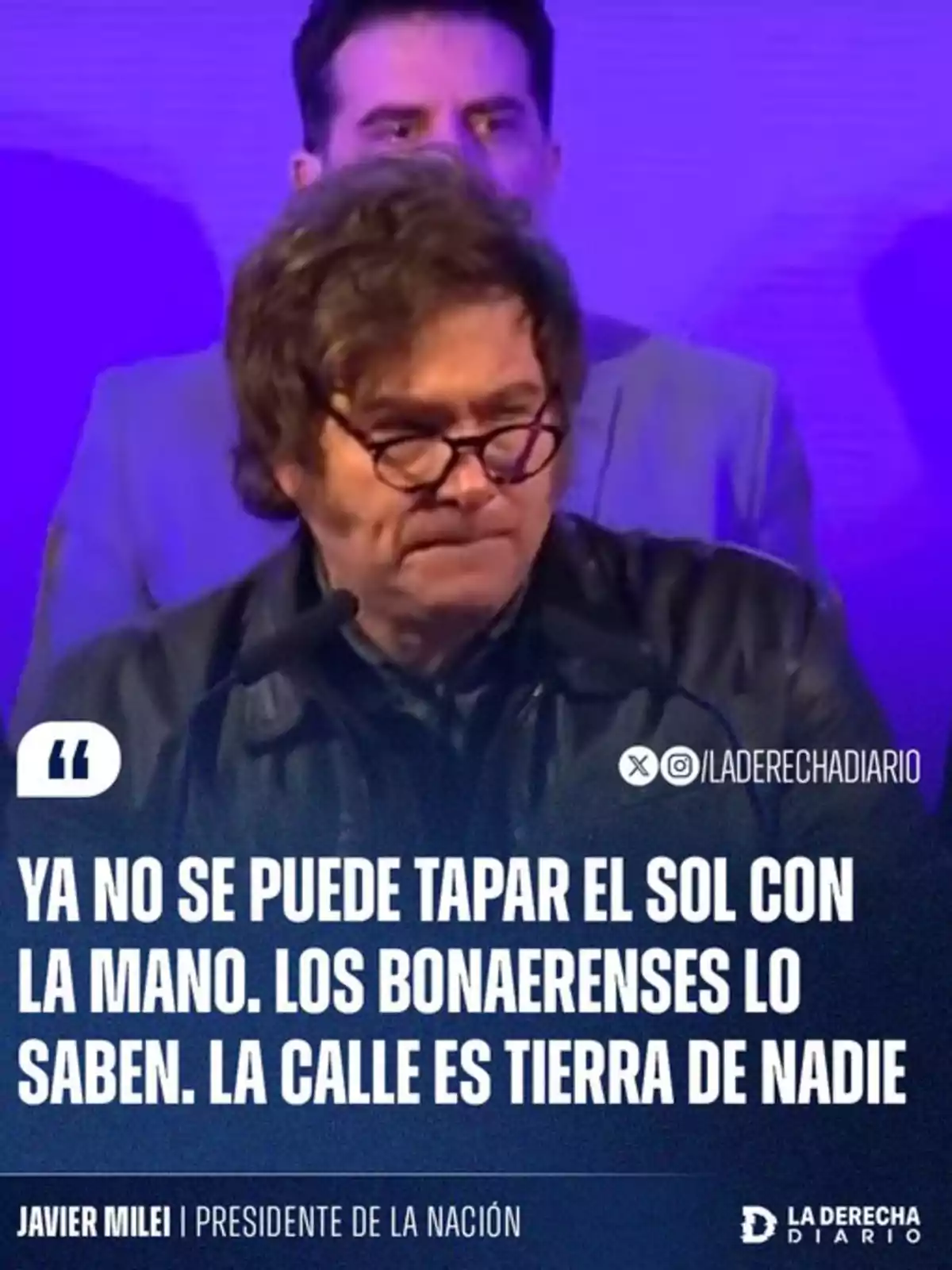 A man with glasses and a serious expression speaks into a microphone, accompanied by another person in the background, against a purple backdrop with text mentioning insecurity in the streets of Buenos Aires.