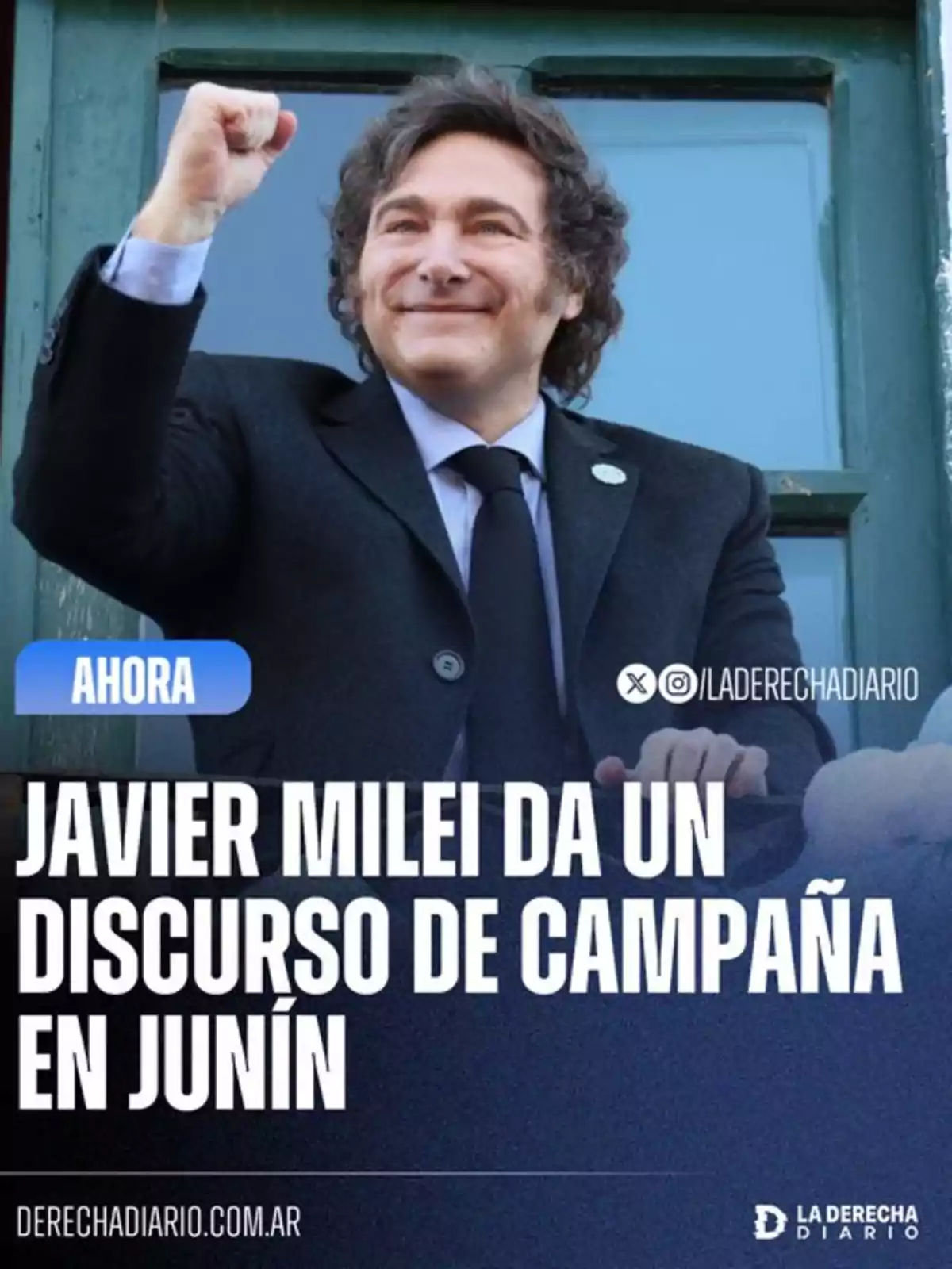 Hombre de cabello ondulado y traje oscuro sonríe y levanta el puño mientras da un discurso de campaña en Junín según el texto en la imagen Hombre de cabello ondulado y traje oscuro sonríe y levanta el puño mientras da un discurso de campaña en Junín según el texto en la imagen