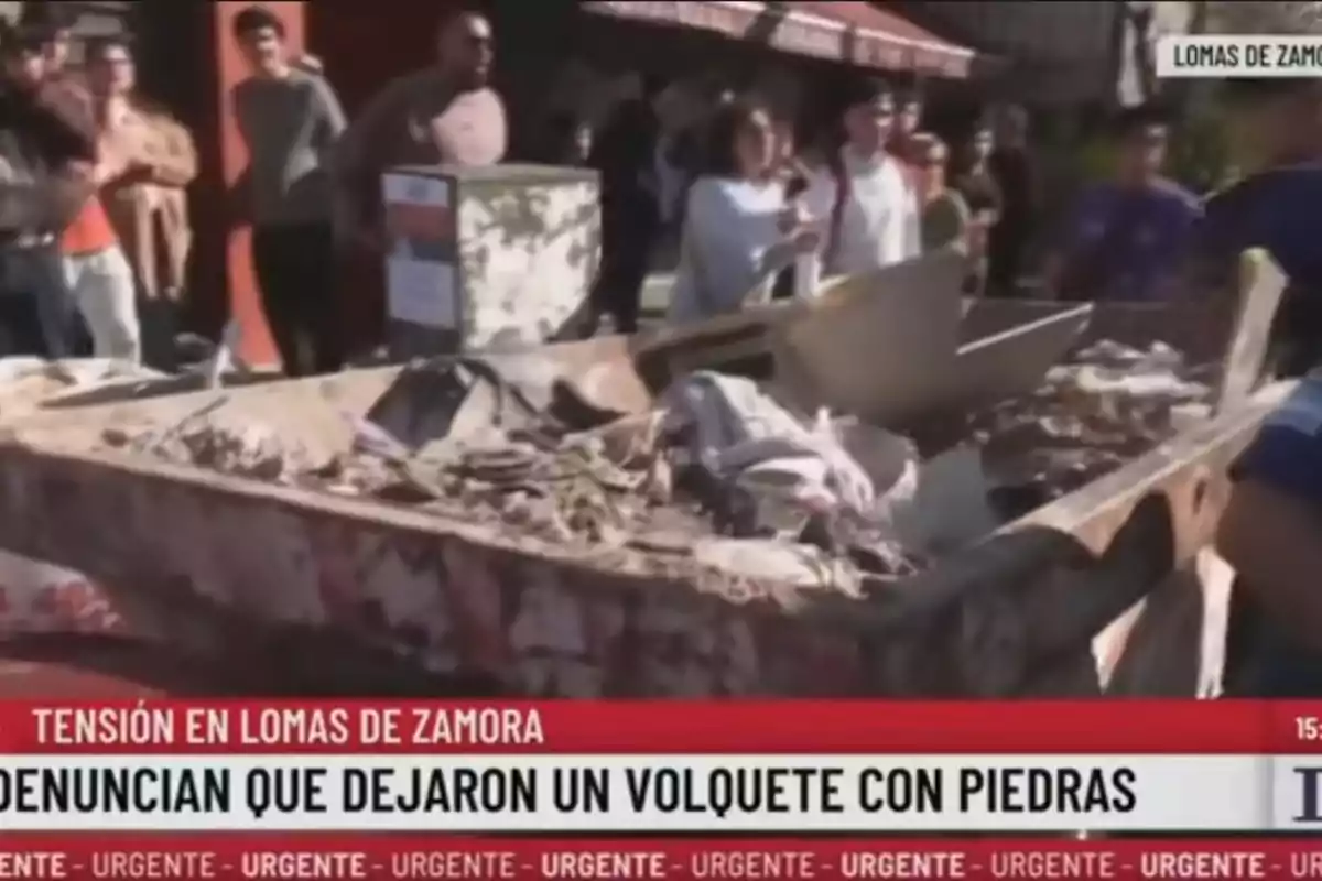 A group of people watches a dump truck full of rubble and stones on a street in Lomas de Zamora while a news report on television covers the complaint about the presence of the dump truck. A group of people watches a dump truck full of rubble and stones on a street in Lomas de Zamora while a news report on television covers the complaint about the presence of the dump truck.