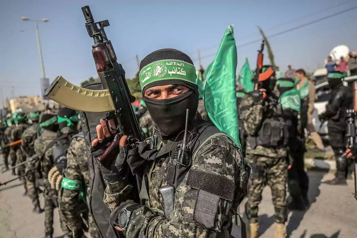 A group of people dressed in camouflage uniforms and green scarves are holding weapons and flags on a street. A group of people dressed in camouflage uniforms and green scarves are holding weapons and flags on a street.