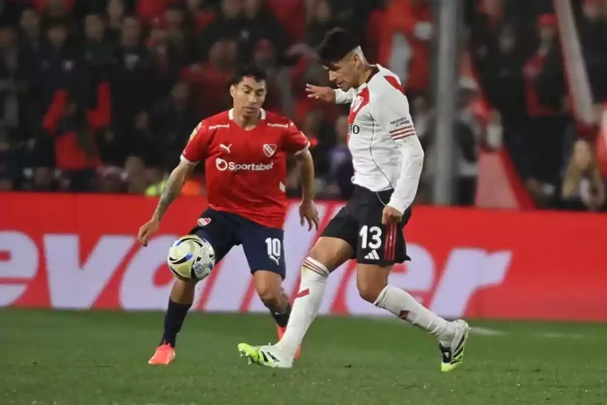 Dos futbolistas disputan el balón durante un partido entre los equipos de River Plate e Independiente