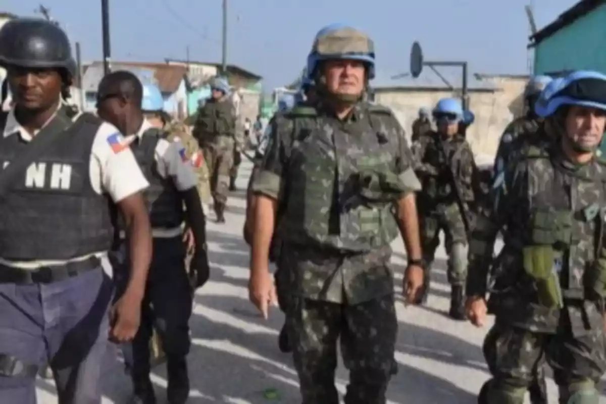 Soldados con cascos azules y chalecos antibalas patrullan una calle junto a policías en uniforme en un entorno urbano Soldados con cascos azules y chalecos antibalas patrullan una calle junto a policías en uniforme en un entorno urbano