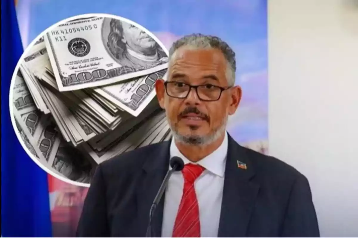 Hombre con gafas y traje hablando frente a un micrófono con una imagen de billetes de cien dólares al fondo
