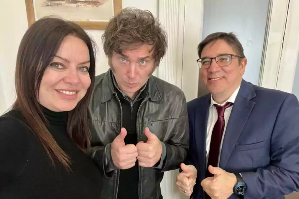 Tres personas posan sonrientes para una foto, dos de ellas levantando ambos pulgares en señal de aprobación