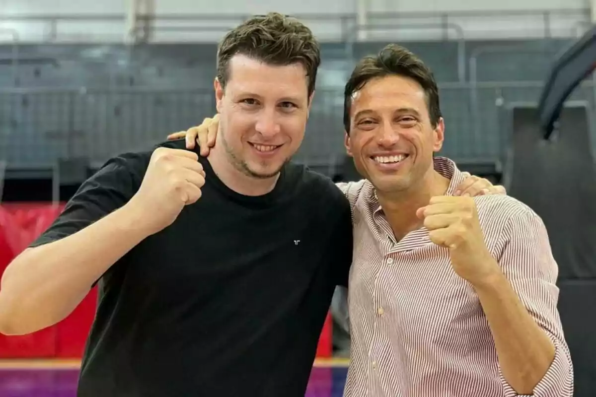 Two men smile and pose together, raising their fists in a gesture of celebration or encouragement. Two men smile and pose together, raising their fists in a gesture of celebration or encouragement.