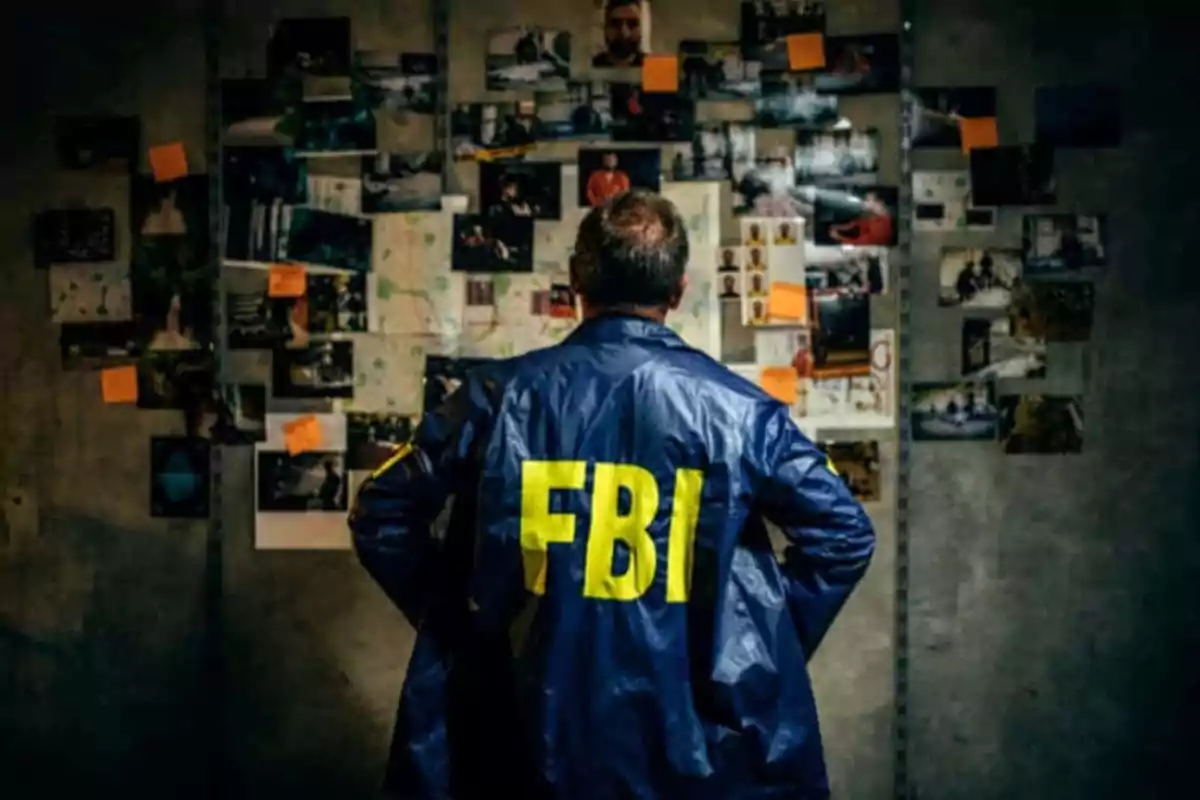 Agente del FBI de espaldas observando un muro lleno de fotos y notas adhesivas en una sala de investigación Agente del FBI de espaldas observando un muro lleno de fotos y notas adhesivas en una sala de investigación