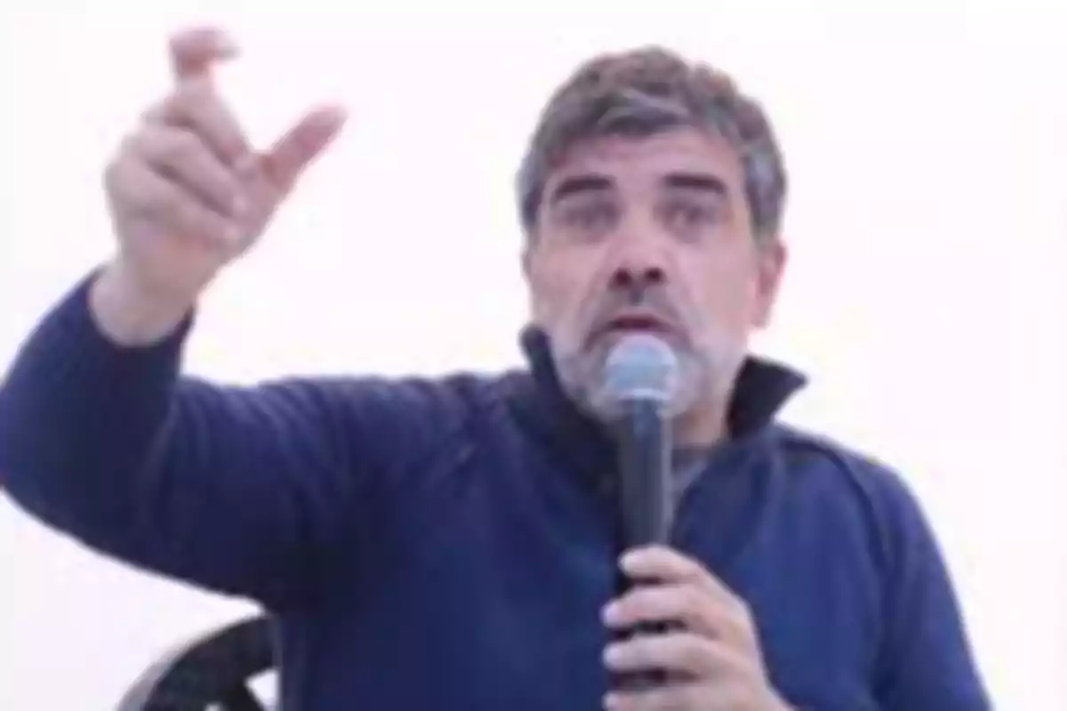 Hombre de cabello canoso hablando por micrófono y gesticulando con la mano Hombre de cabello canoso hablando por micrófono y gesticulando con la mano