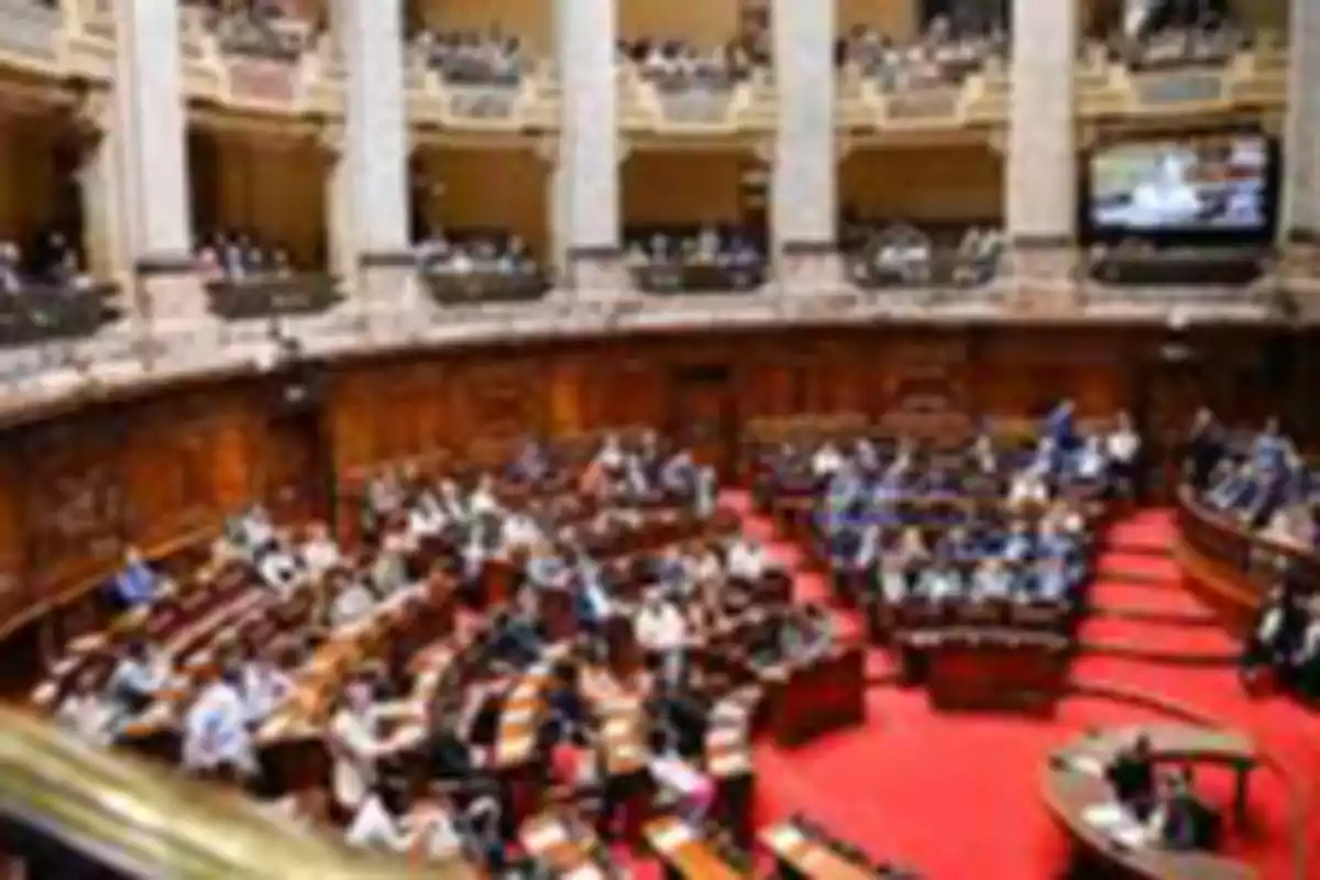 People gathered in a parliamentary chamber with wooden seats and a red carpet People gathered in a parliamentary chamber with wooden seats and a red carpet