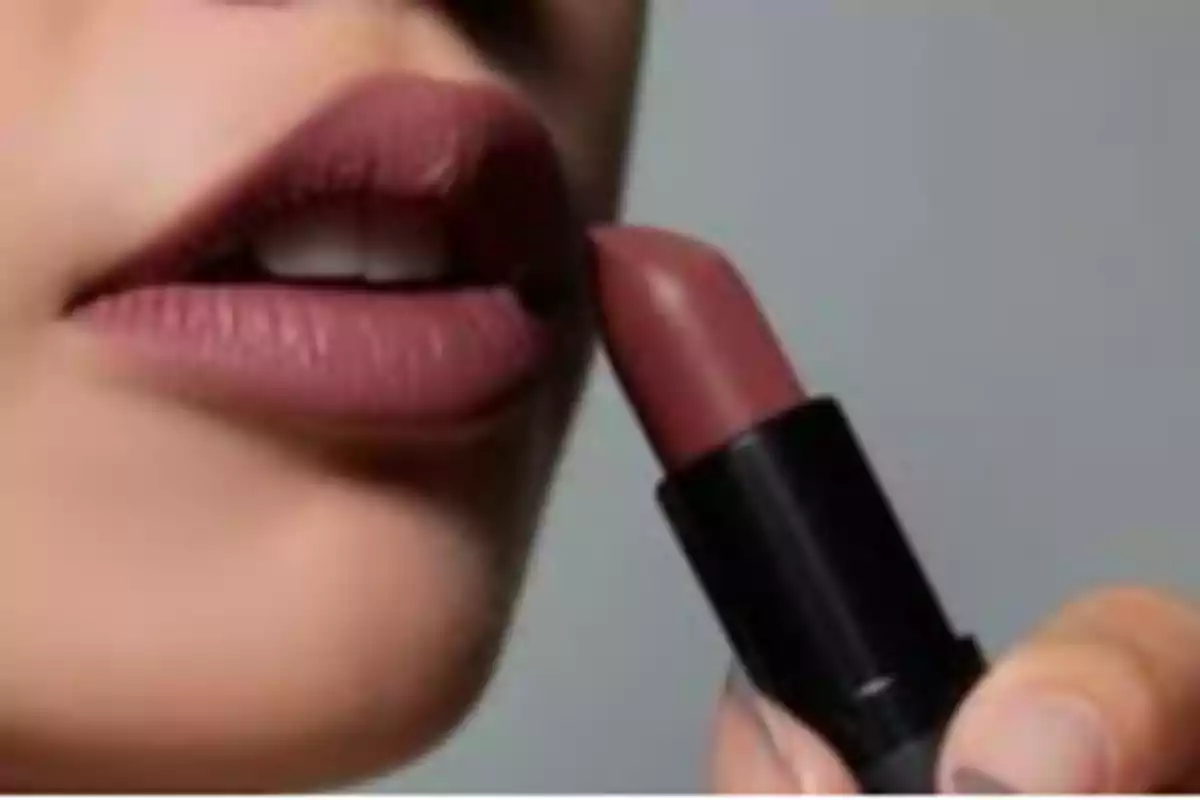 Persona aplicando labial color nude en sus labios Persona aplicando labial color nude en sus labios