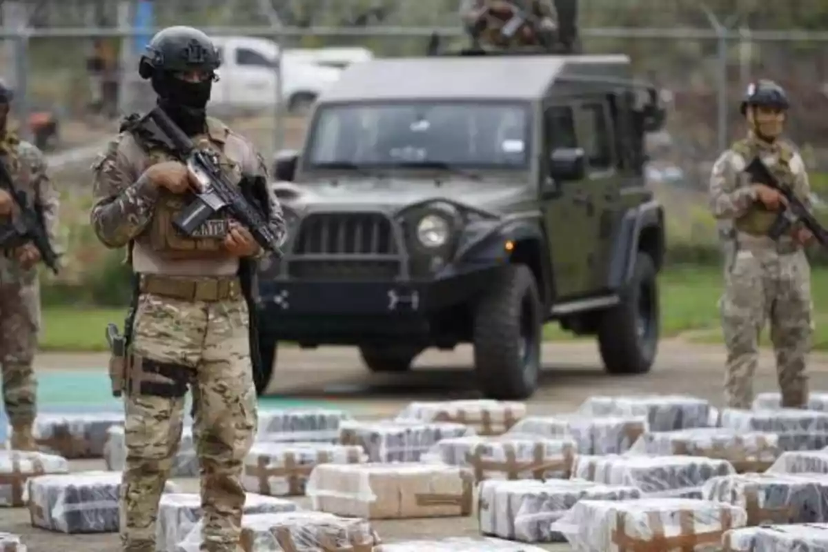 Armed soldiers guard numerous plastic-wrapped packages in front of an off-road vehicle. Armed soldiers guard numerous plastic-wrapped packages in front of an off-road vehicle.