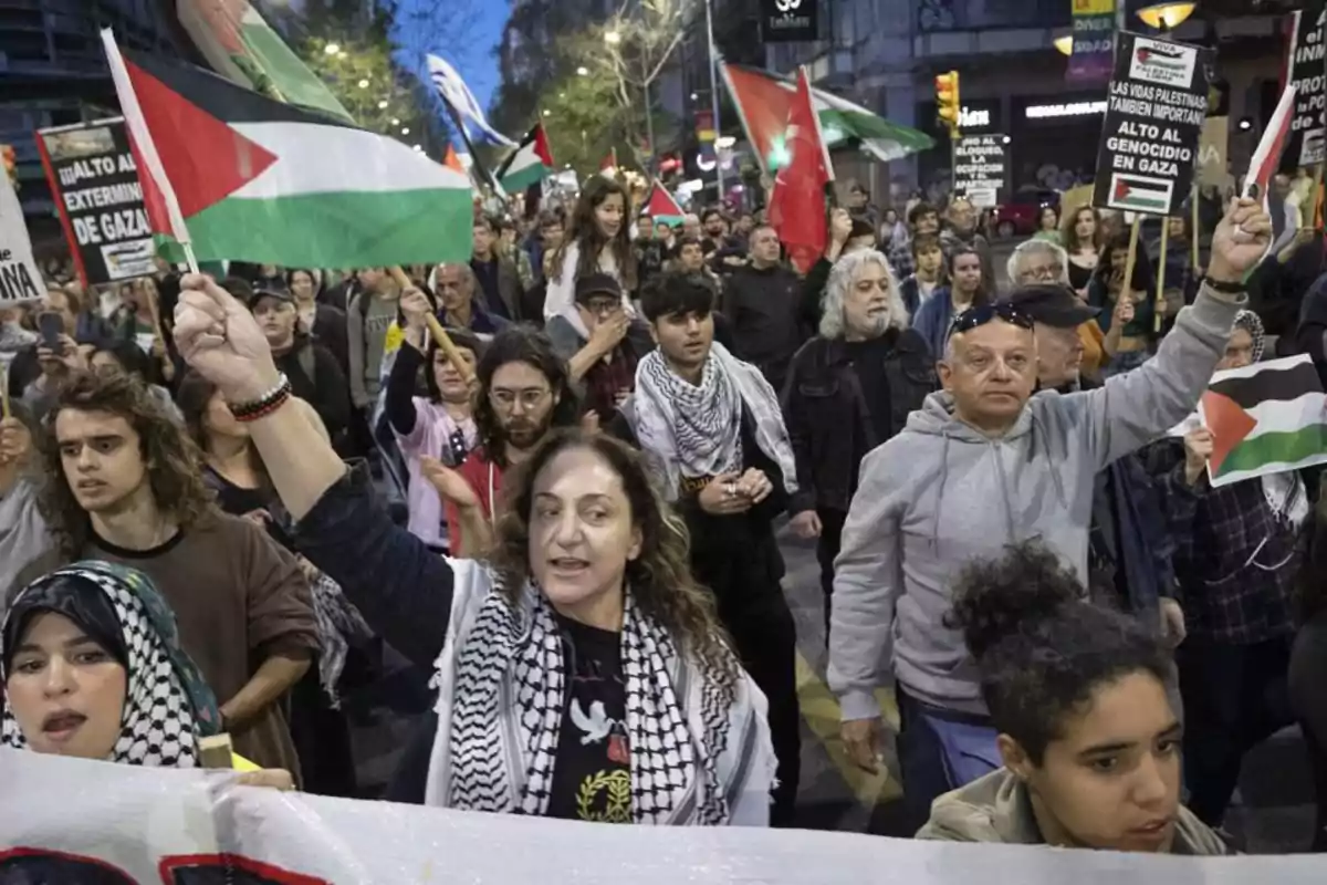 Demonstration with people marching and raising Palestinian flags and banners on an urban street