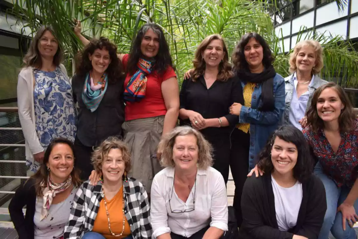 Group of women smiling outdoors with green plants in the background