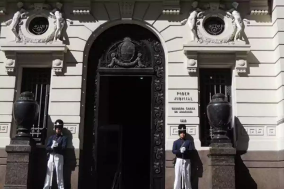 Fachada de un edificio judicial con dos guardias uniformados de pie a ambos lados de la entrada principal