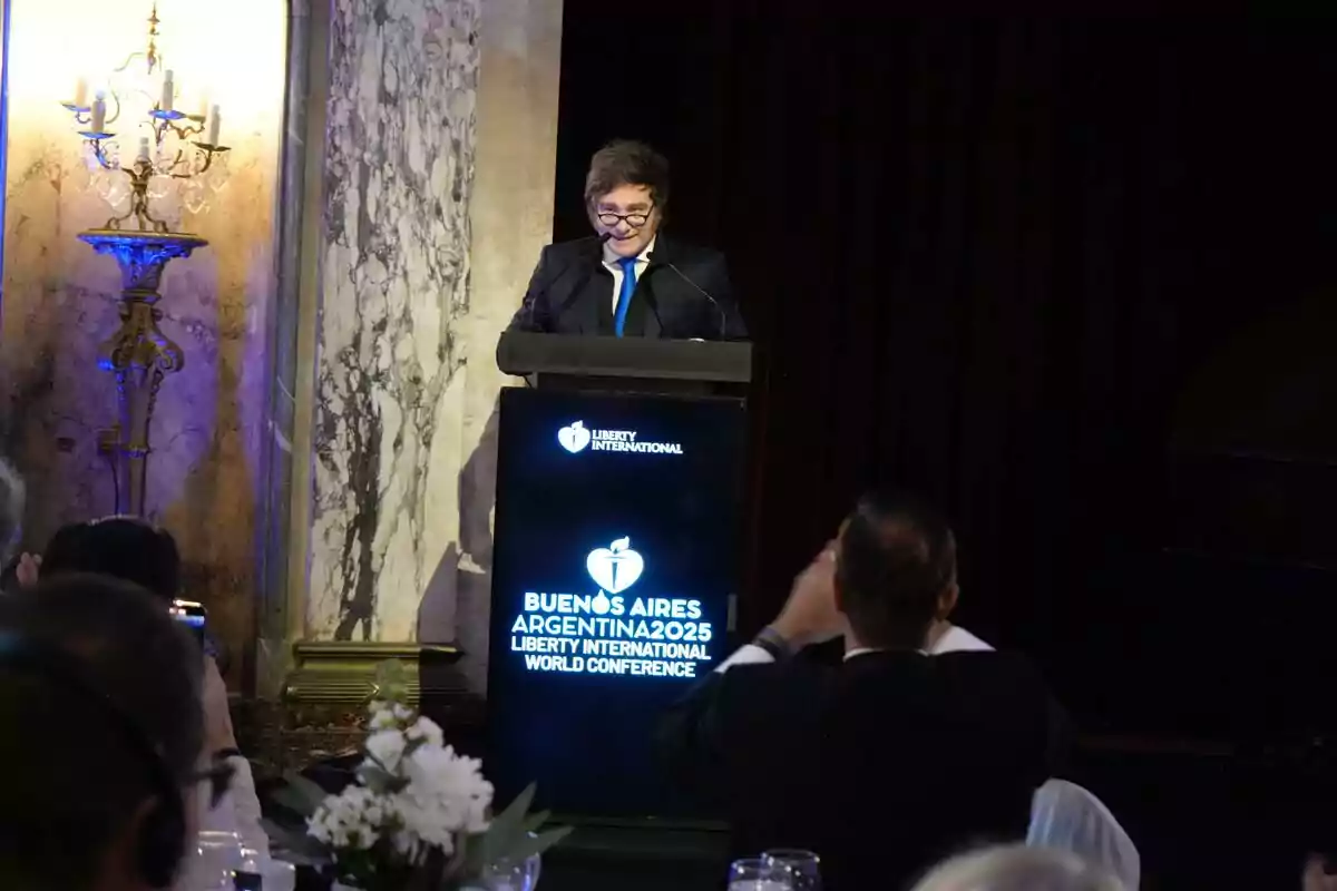 Persona de pie hablando en un podio iluminado durante una conferencia en Buenos Aires Argentina 2025 con público sentado al frente y decoración elegante en el fondo
