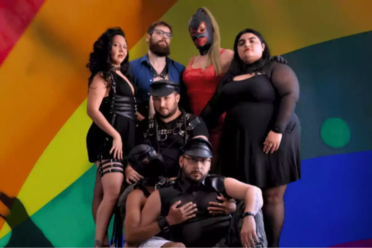 Six people pose in leather clothing and striking outfits in front of a colorful background.
