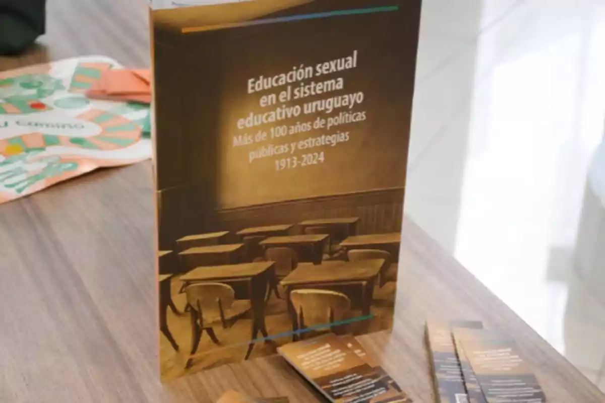 Book titled Sexual Education in the Uruguayan Education System: Over 100 Years of Public Policies and Strategies 1913-2024 on a table alongside several brochures and an educational game board in the background Book titled Sexual Education in the Uruguayan Education System: Over 100 Years of Public Policies and Strategies 1913-2024 on a table alongside several brochures and an educational game board in the background