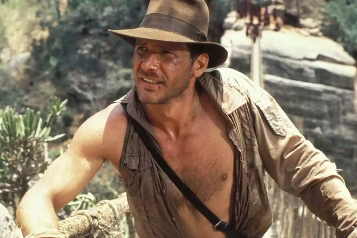 Man with a hat and an open jersey crossing a bridge in a jungle setting Man with a hat and an open jersey crossing a bridge in a jungle setting