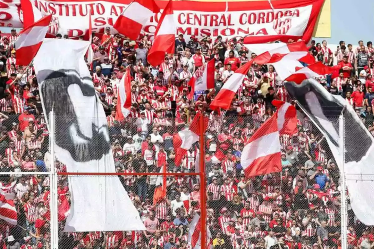 Hinchas de fútbol con camisetas rojas y blancas animan en la tribuna con banderas y pancartas en un estadio lleno Hinchas de fútbol con camisetas rojas y blancas animan en la tribuna con banderas y pancartas en un estadio lleno